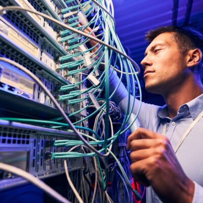 Focused serious experienced data center IT technician doing performance checking of twisted-pair cables